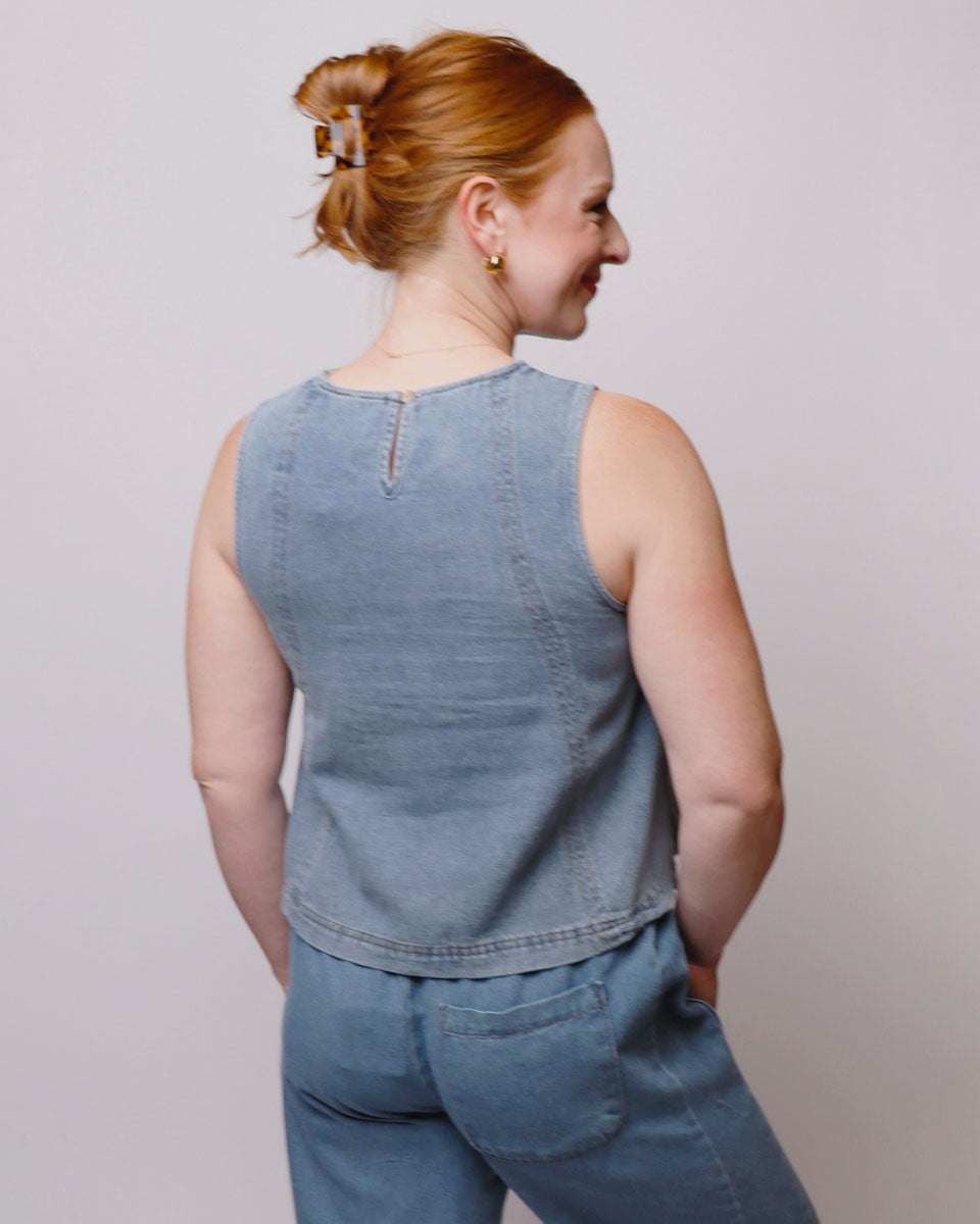 Woman wearing a blue sleeveless top and pants against a plain background