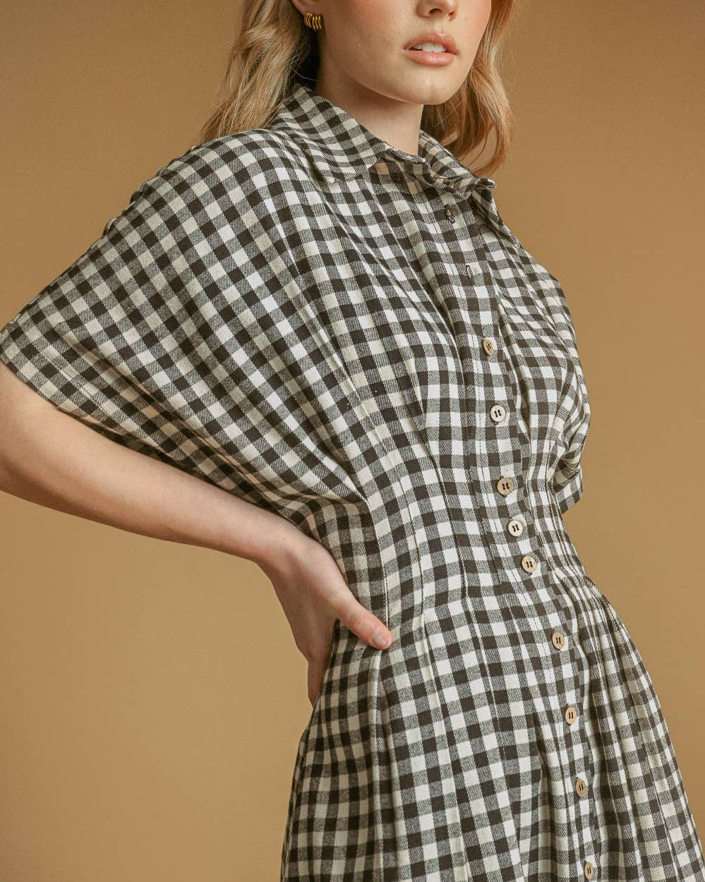 Woman wearing a checkered dress against a beige background