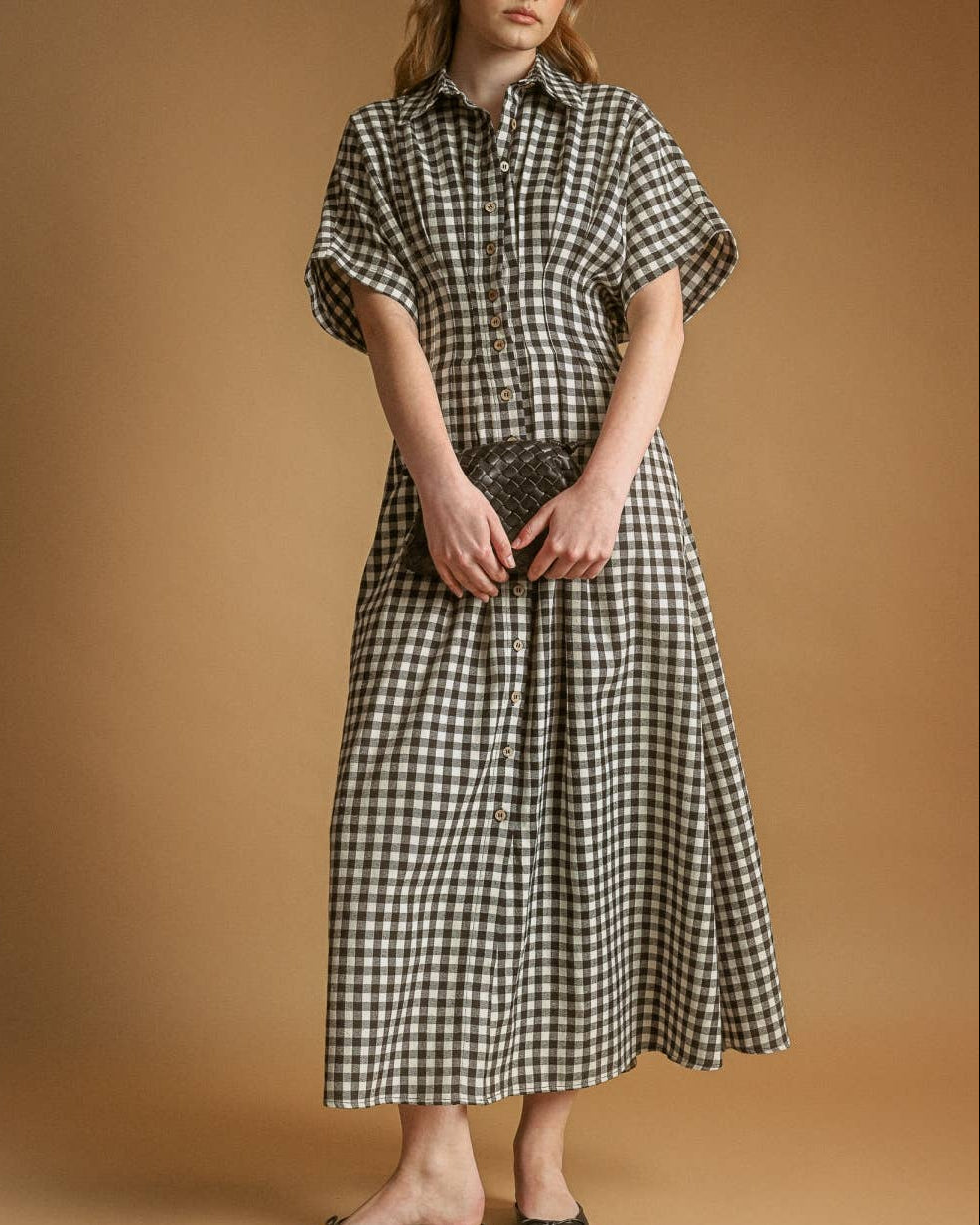 Woman wearing a black and white checkered dress against a brown background