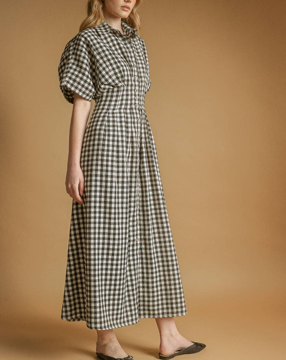 Woman wearing a black and white checkered dress against a brown background