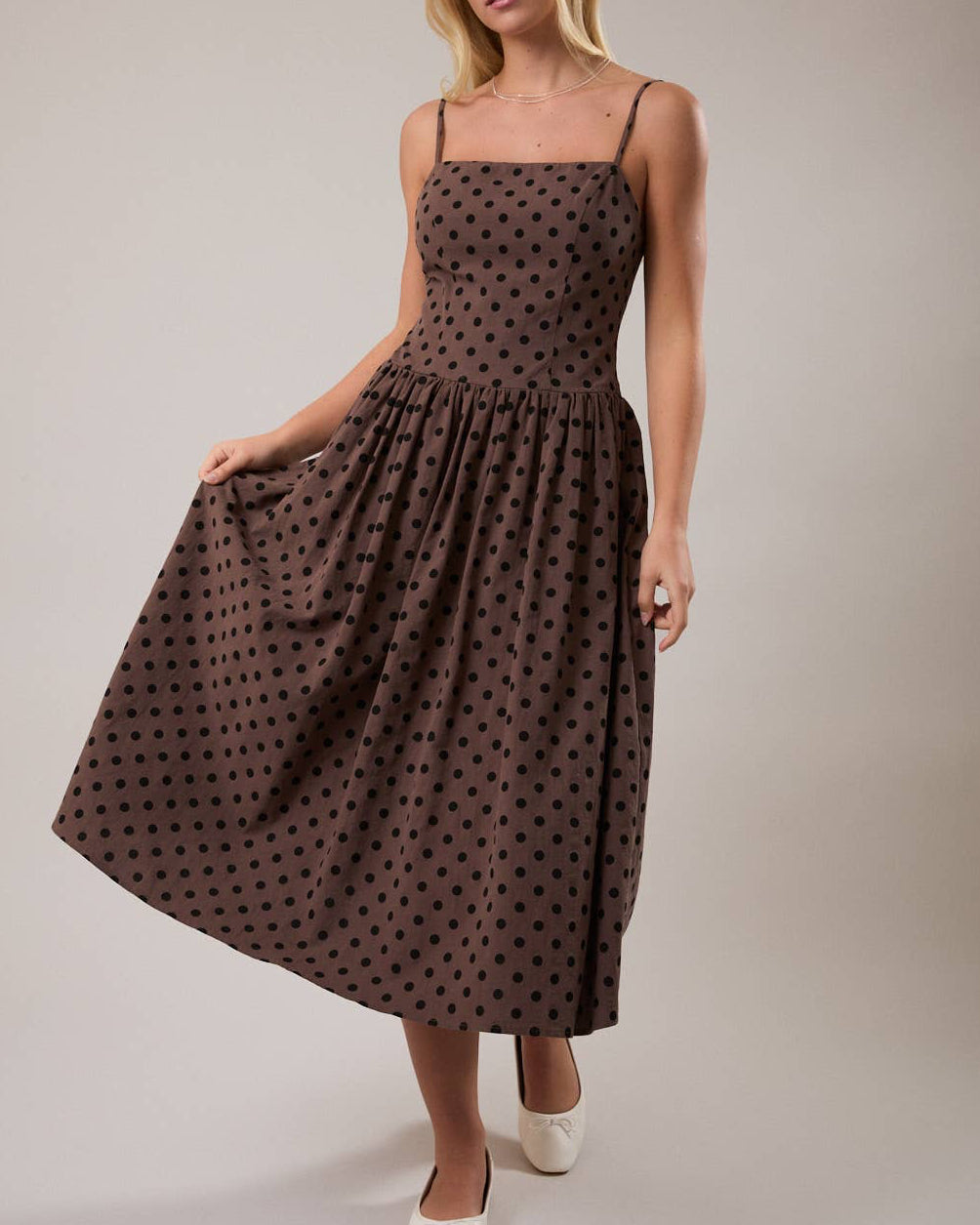 Woman wearing a brown polka dot dress on a plain background