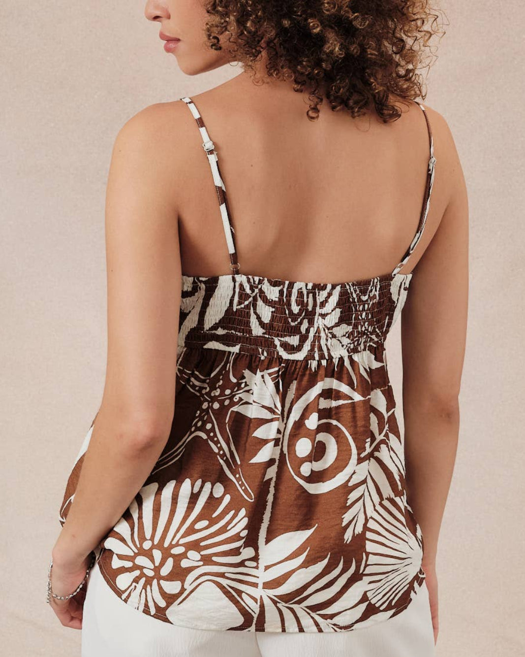 Model wearing a brown and white floral patterned top against a neutral background back view