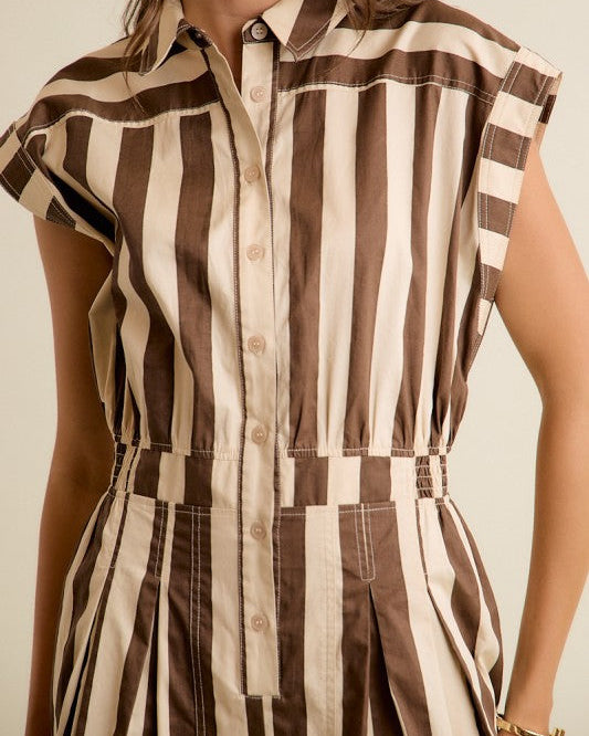 A close-up of a woman wearing a brown and beige vertically striped jumpsuit with a button-down front and cap sleeves.