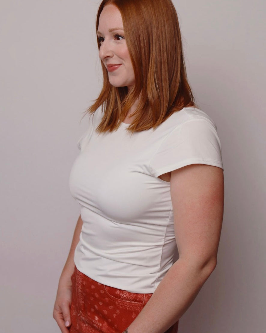 Woman wearing a white t-shirt and red pants against a plain background