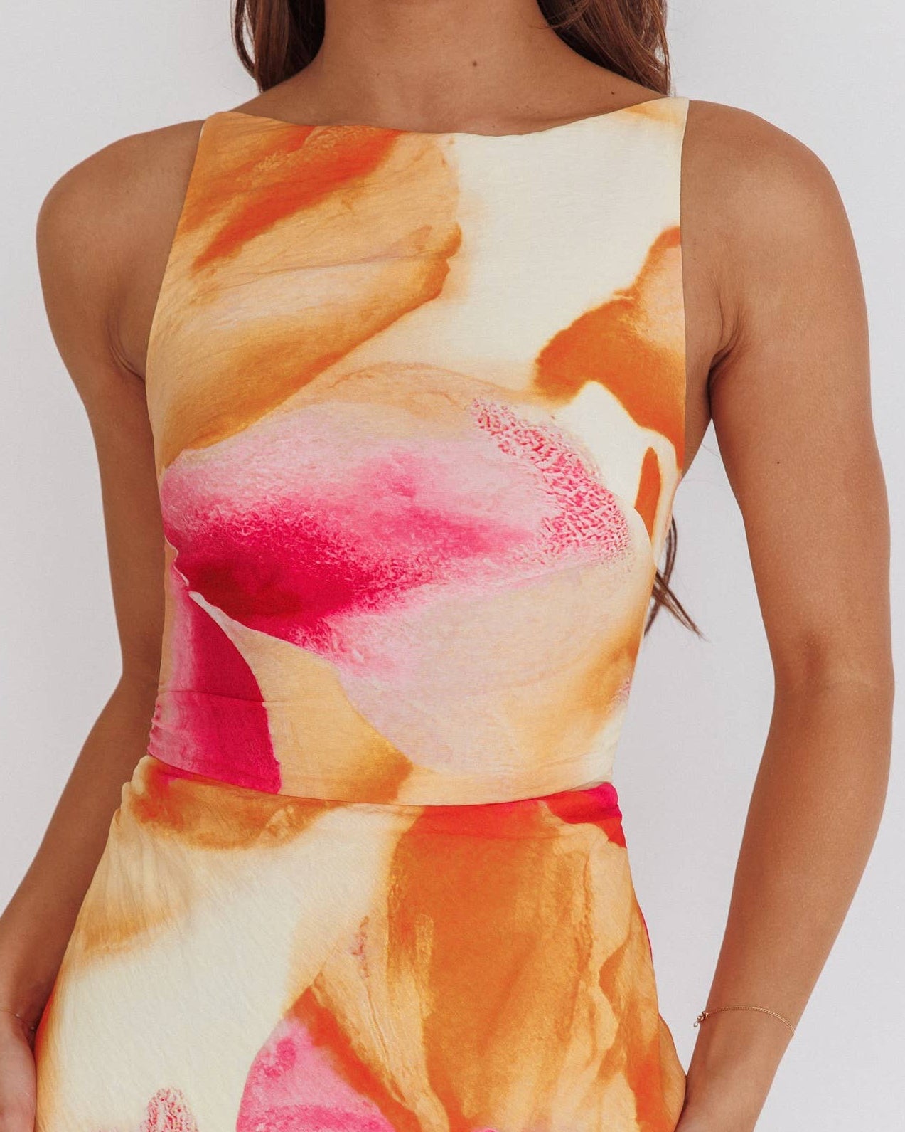 Woman wearing a sleeveless dress with floral pattern on a plain background