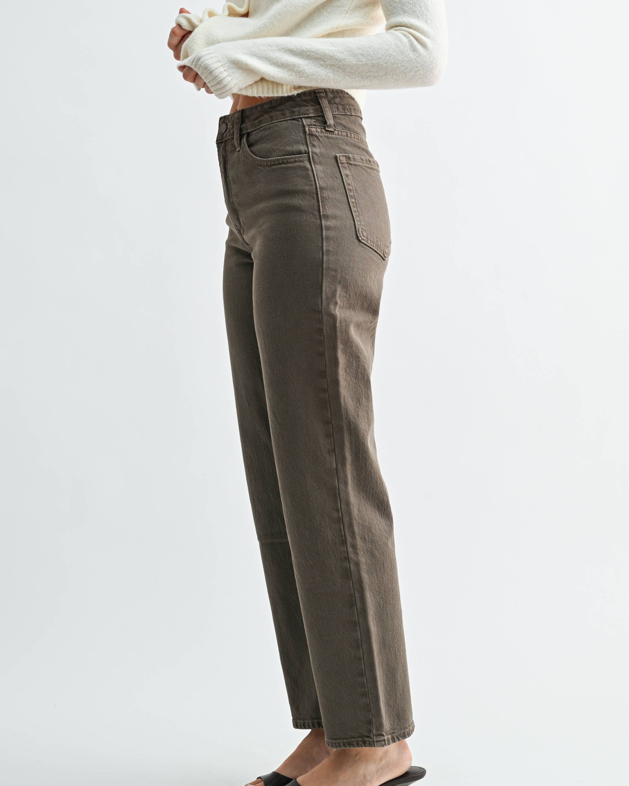 A model wearing a pair of vintage brown straight-leg jeans on a neutral background. Side view