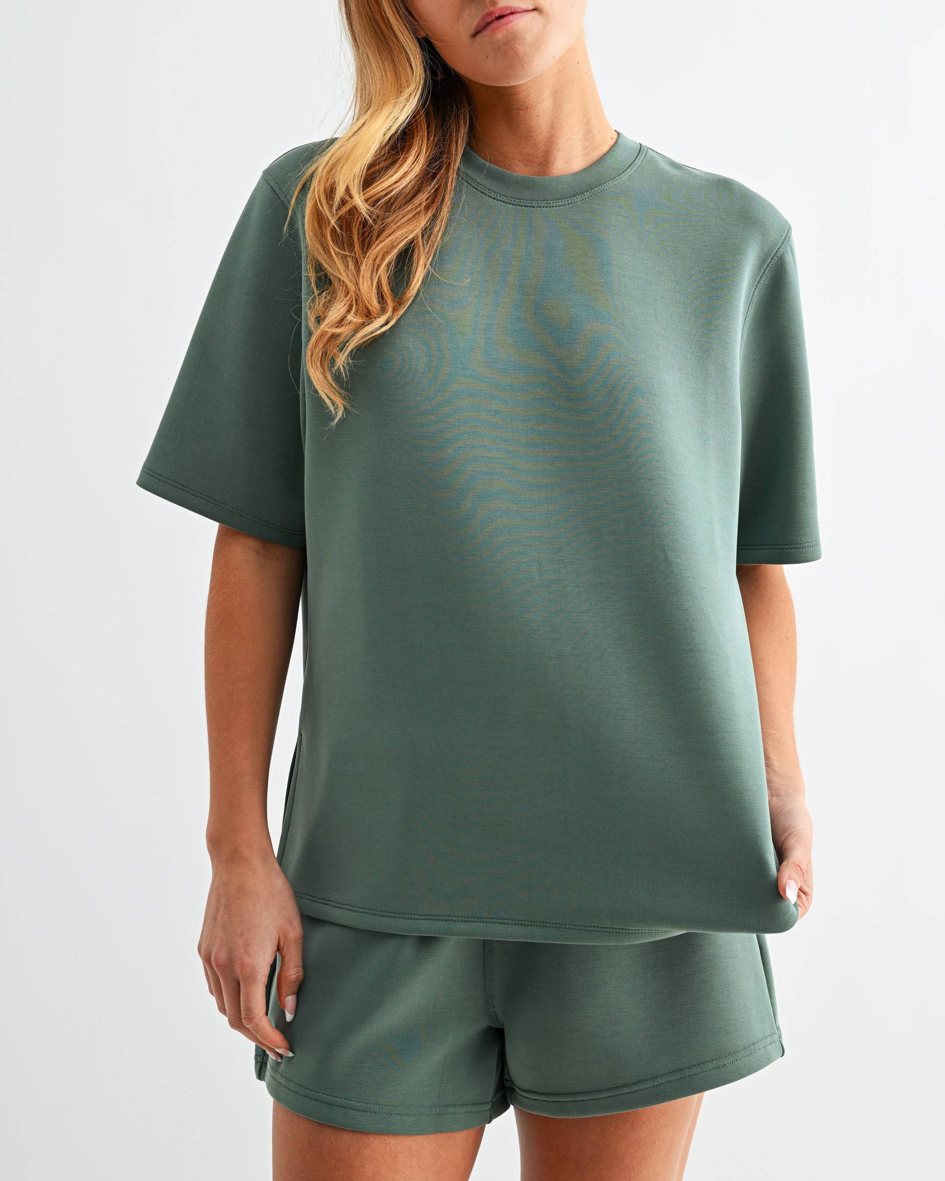 Model wearing a green t-shirt and shorts set on a neutral background