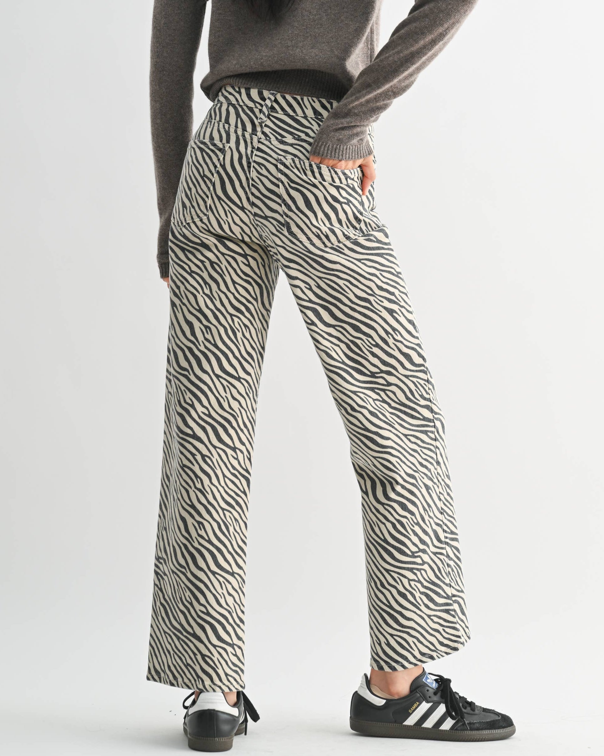 Person wearing a gray sweater and zebra-striped pants on a white background