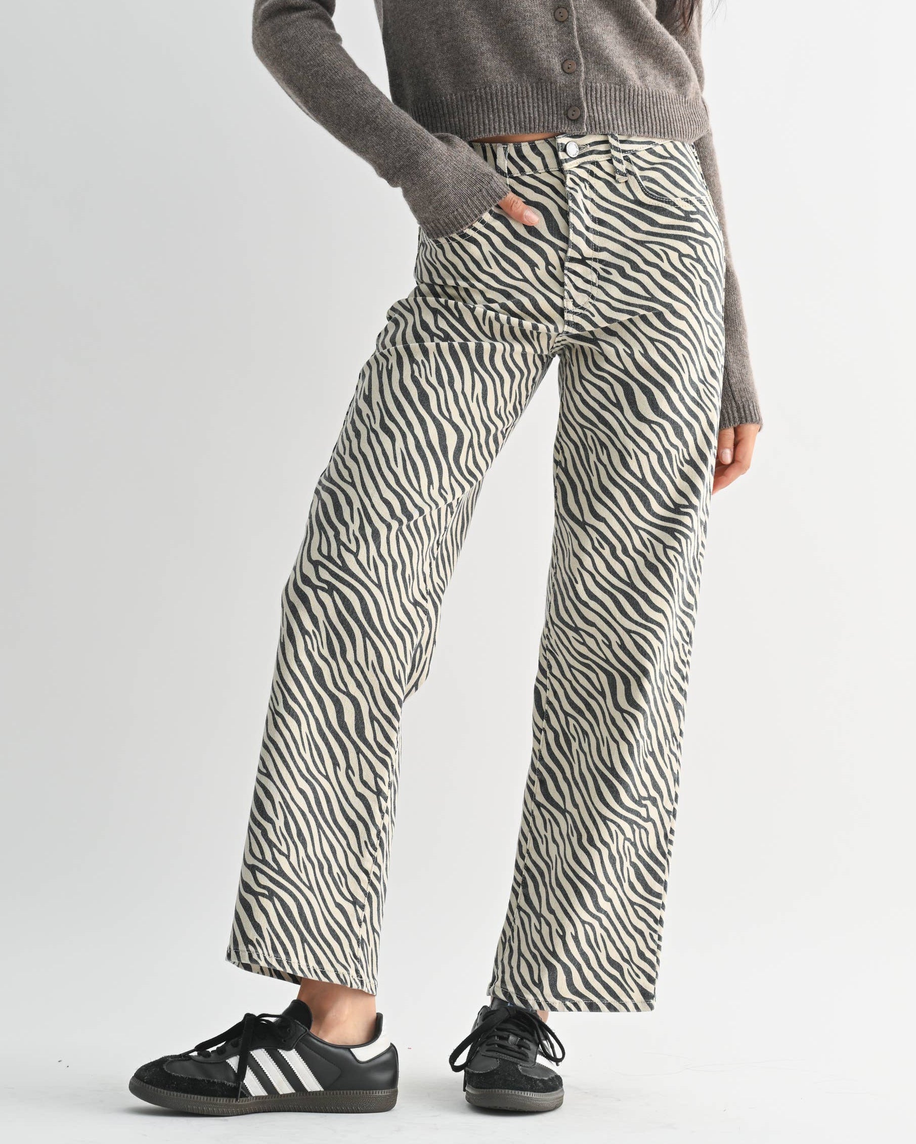 Woman wearing a gray sweater and zebra print pants on a white background