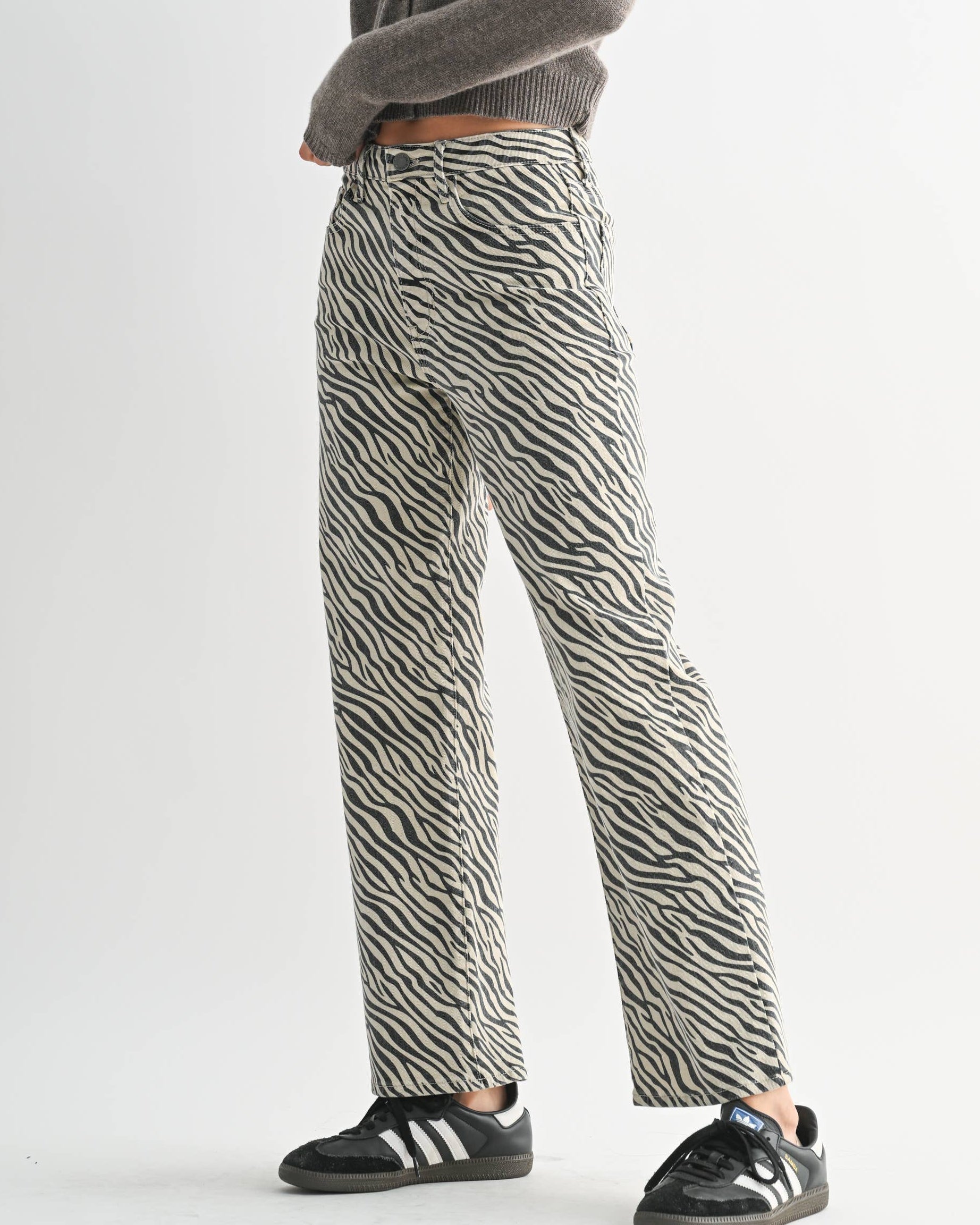 Person wearing a gray sweater and zebra print pants on a white background