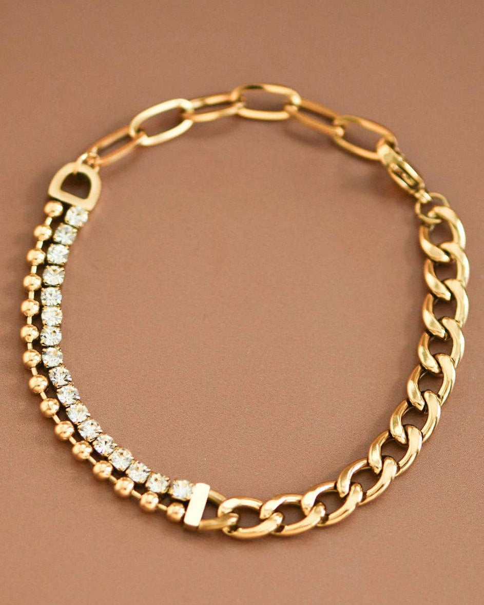 Gold chain necklace with embedded crystals on a brown background