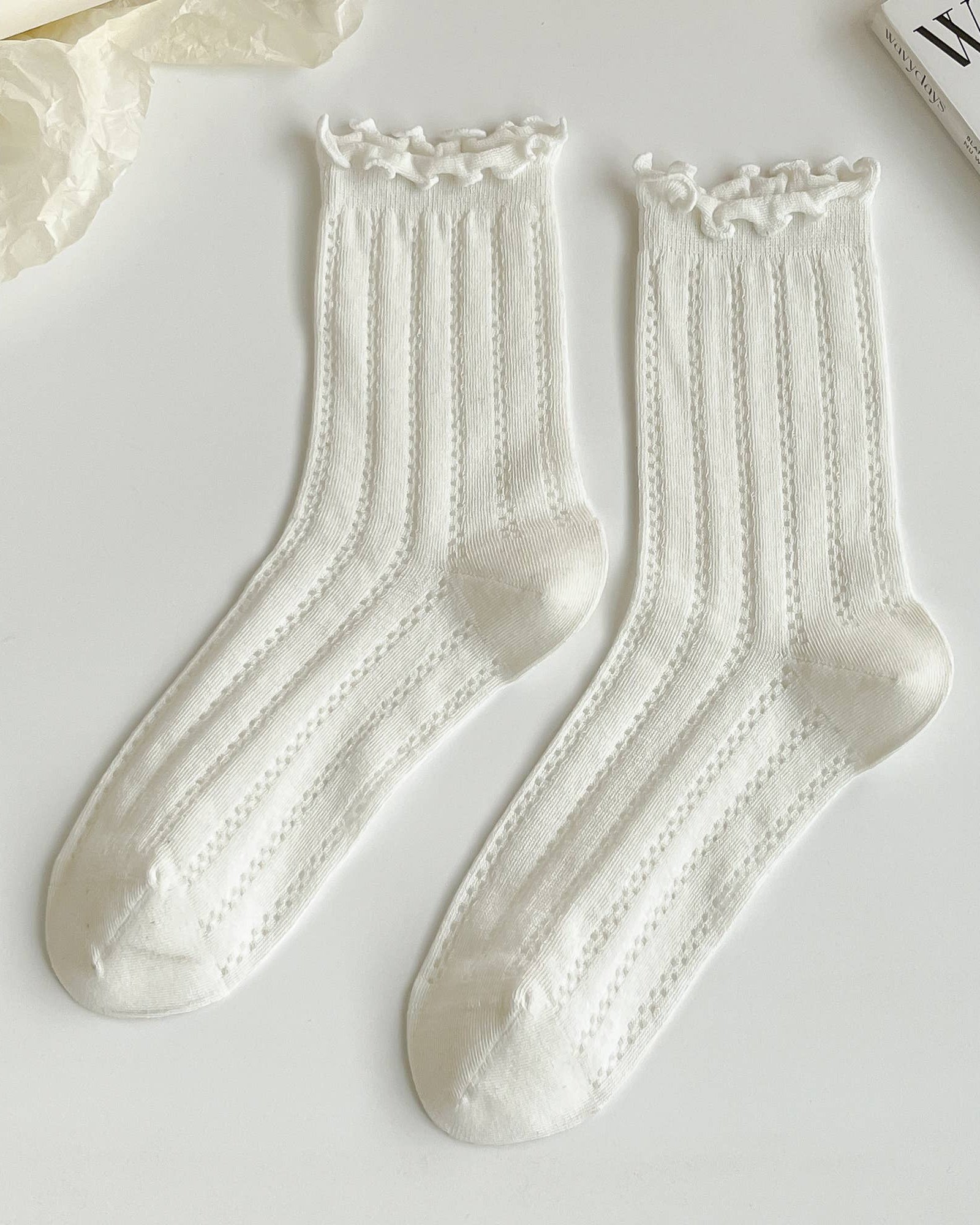 Pair of white socks with lace details on a light gray background