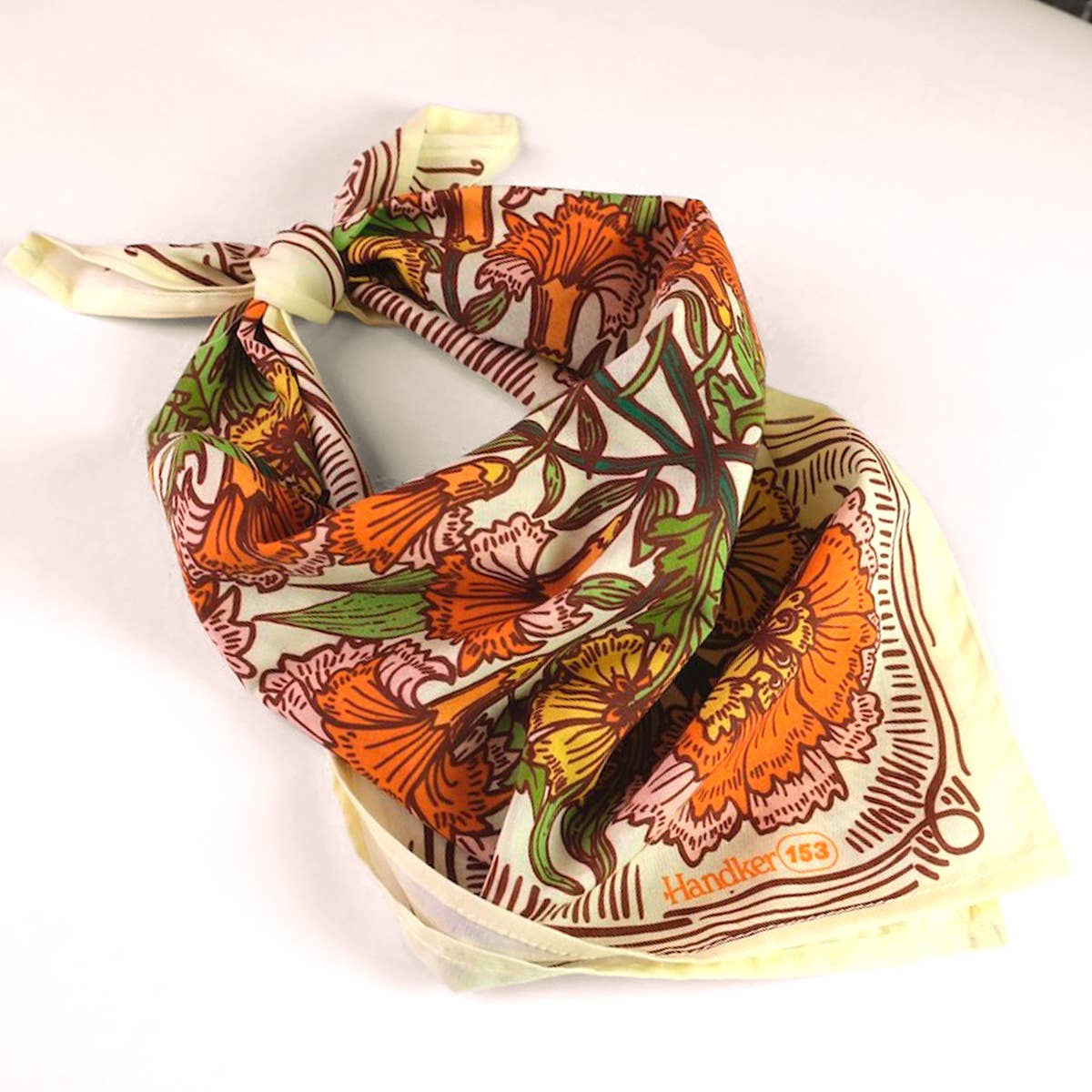 Floral patterned scarf with orange and green colors on a white background