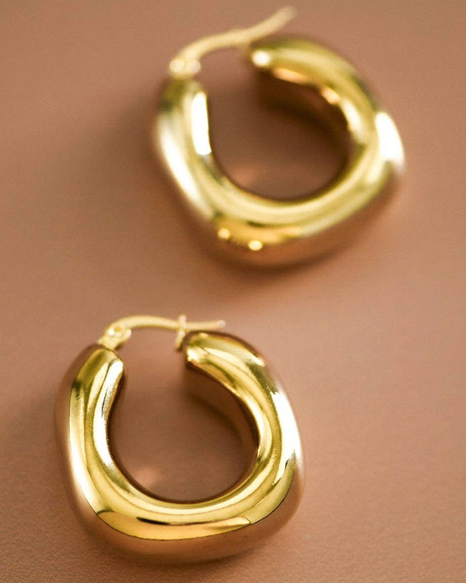 Gold hoop earrings on a brown background