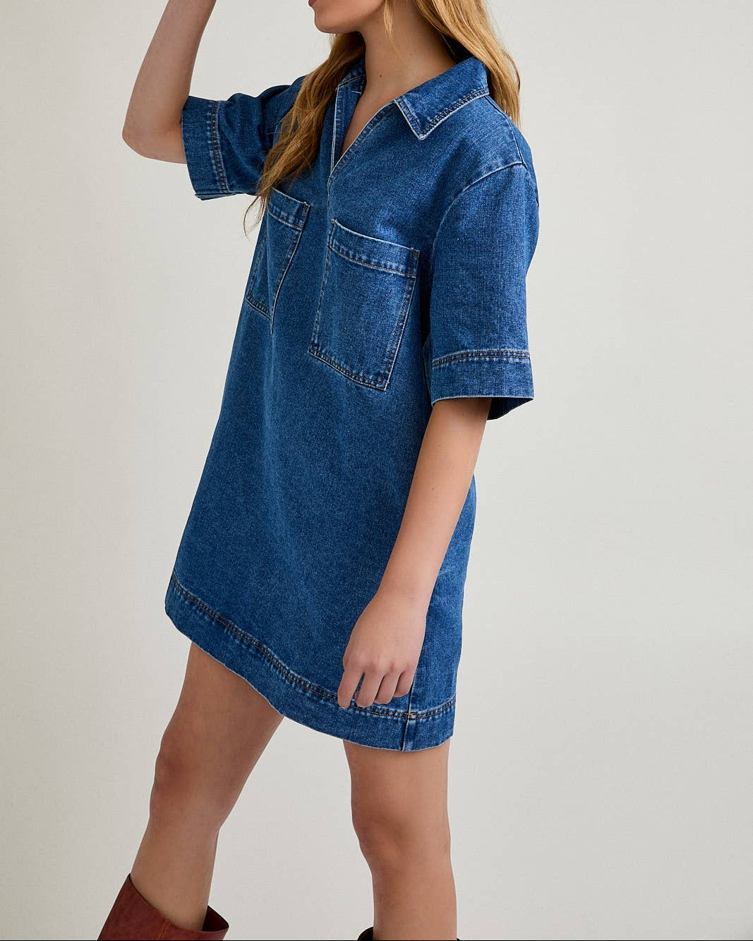 Woman wearing a blue denim dress and red cap on a plain background