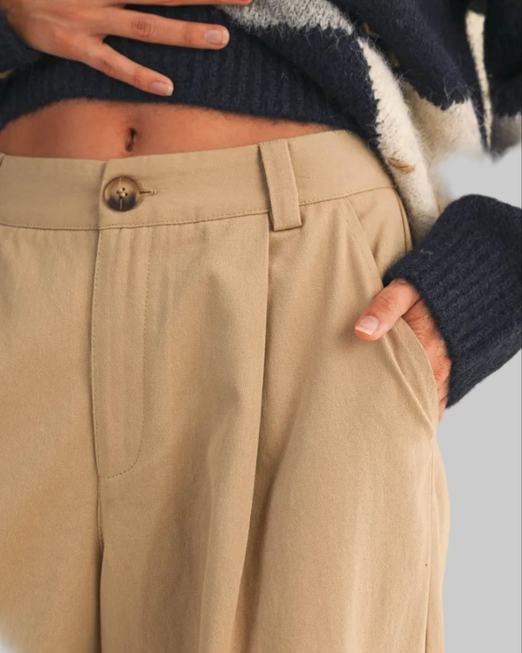Beige pants worn with a patterned sweater on a neutral background