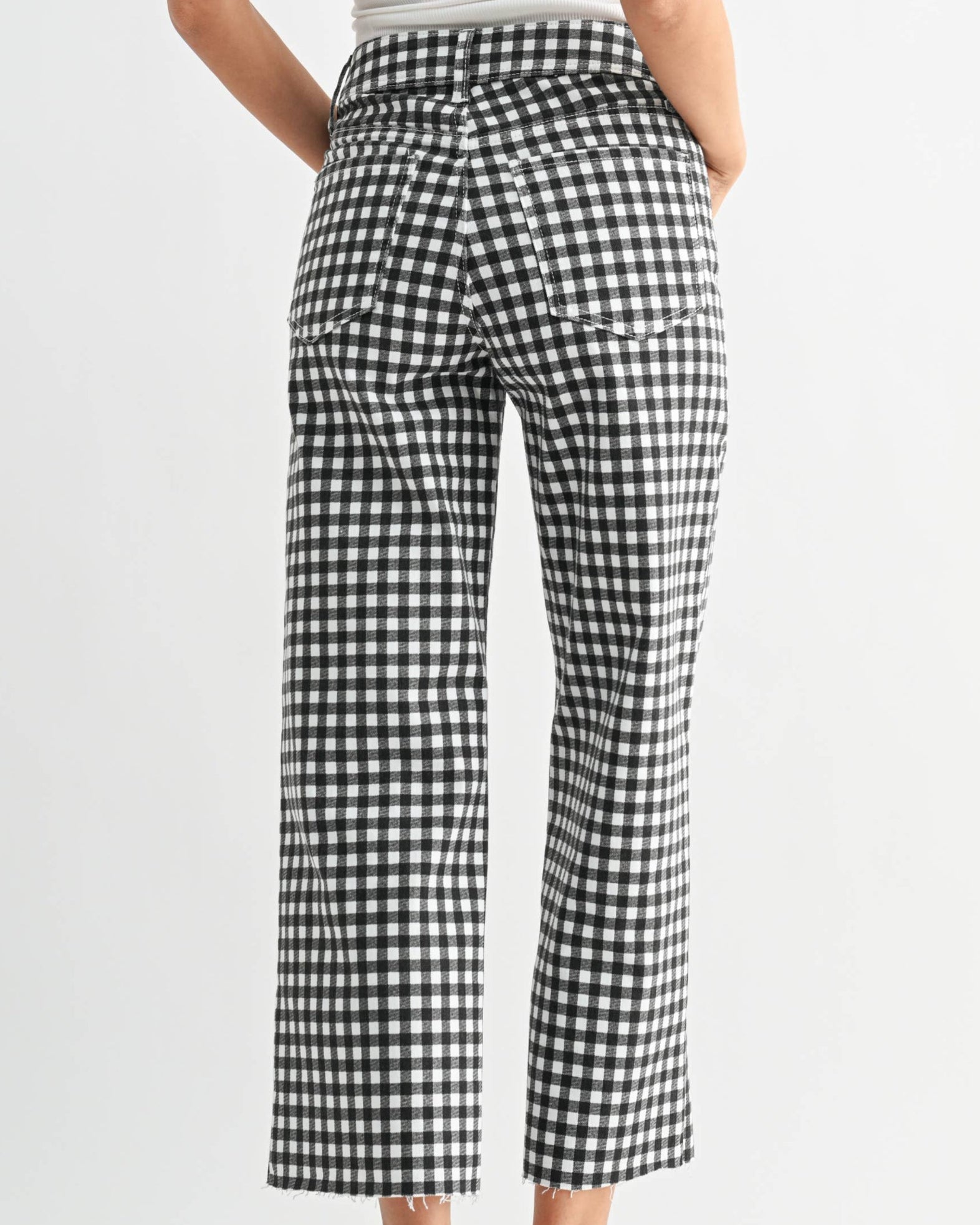Woman wearing a white top and black and white checkered pants on a white background