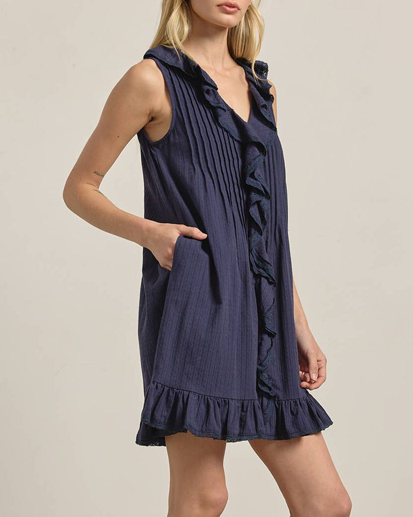 Woman wearing a navy blue dress with ruffles on a beige background