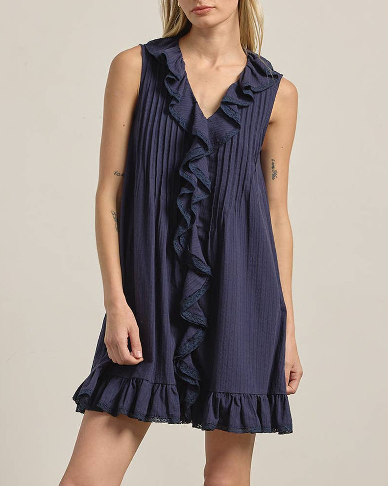Woman wearing a navy blue dress with ruffles on a plain background