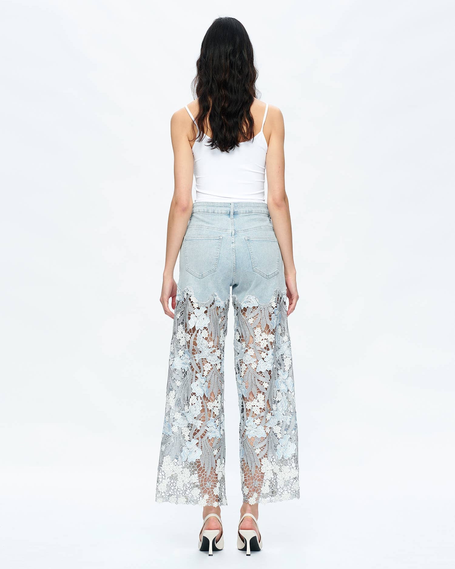 Woman wearing light blue floral lace pants on a white background