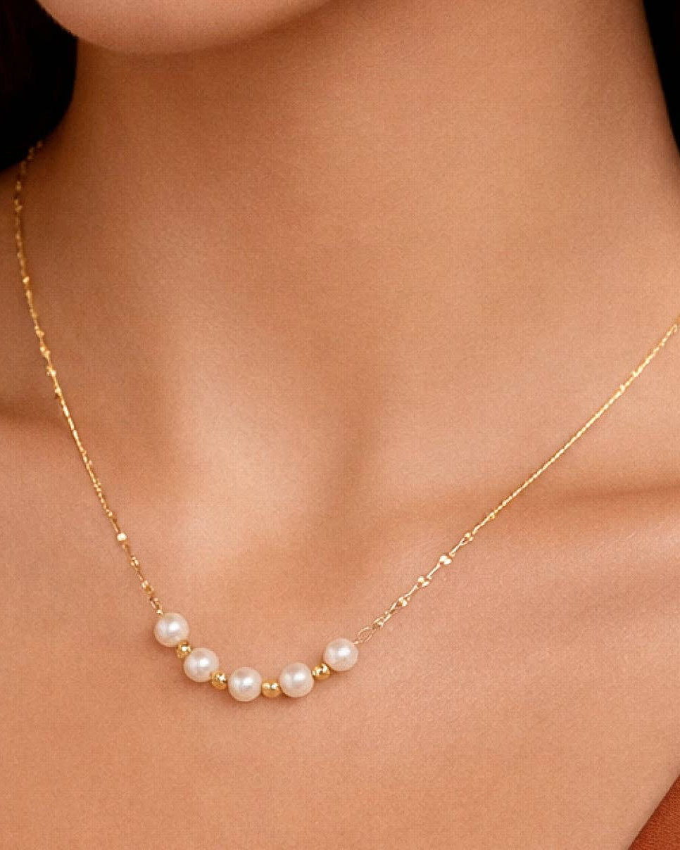 Gold necklace with pearls on a person's neck