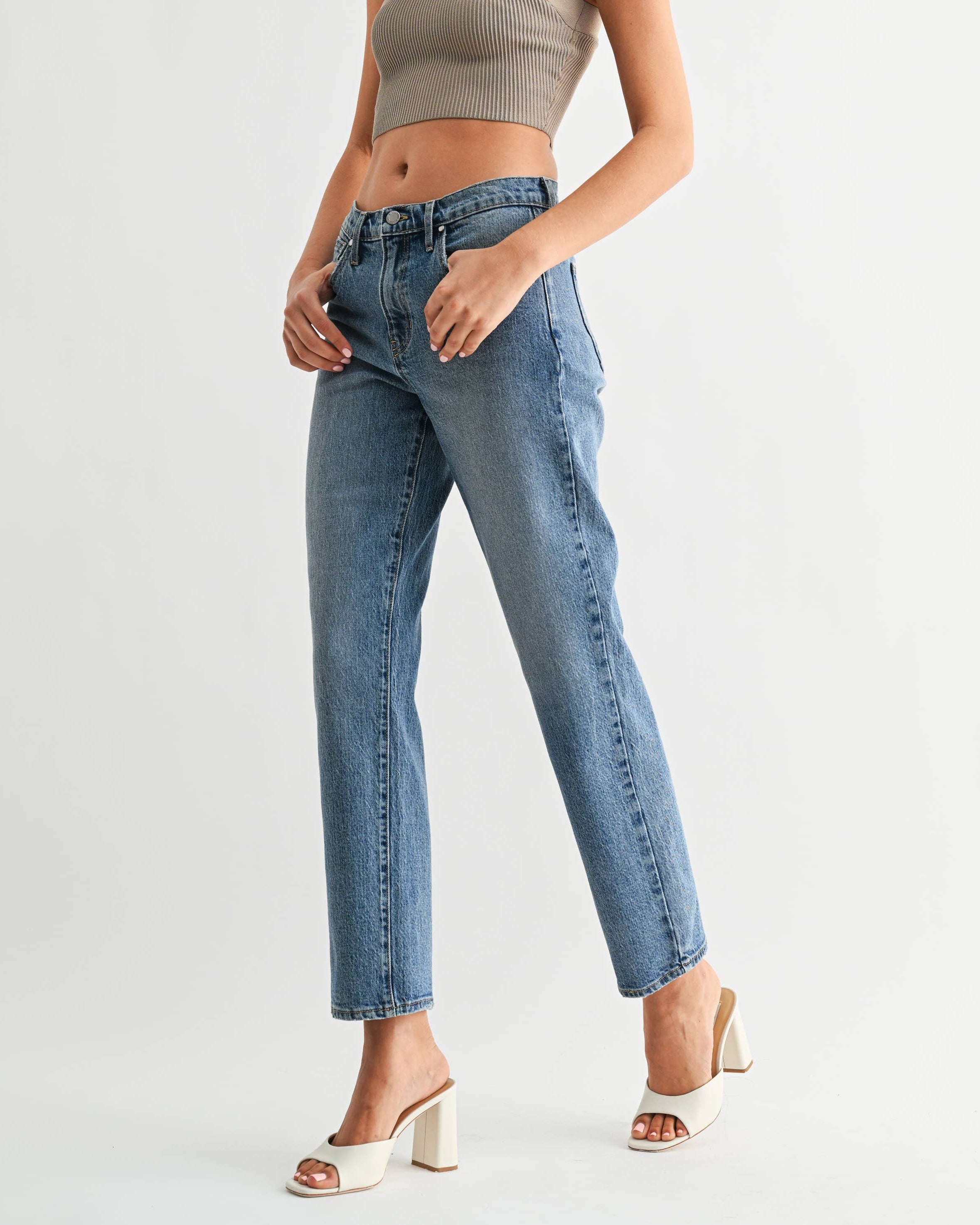 Woman wearing a halter top and high-waisted jeans on a white background