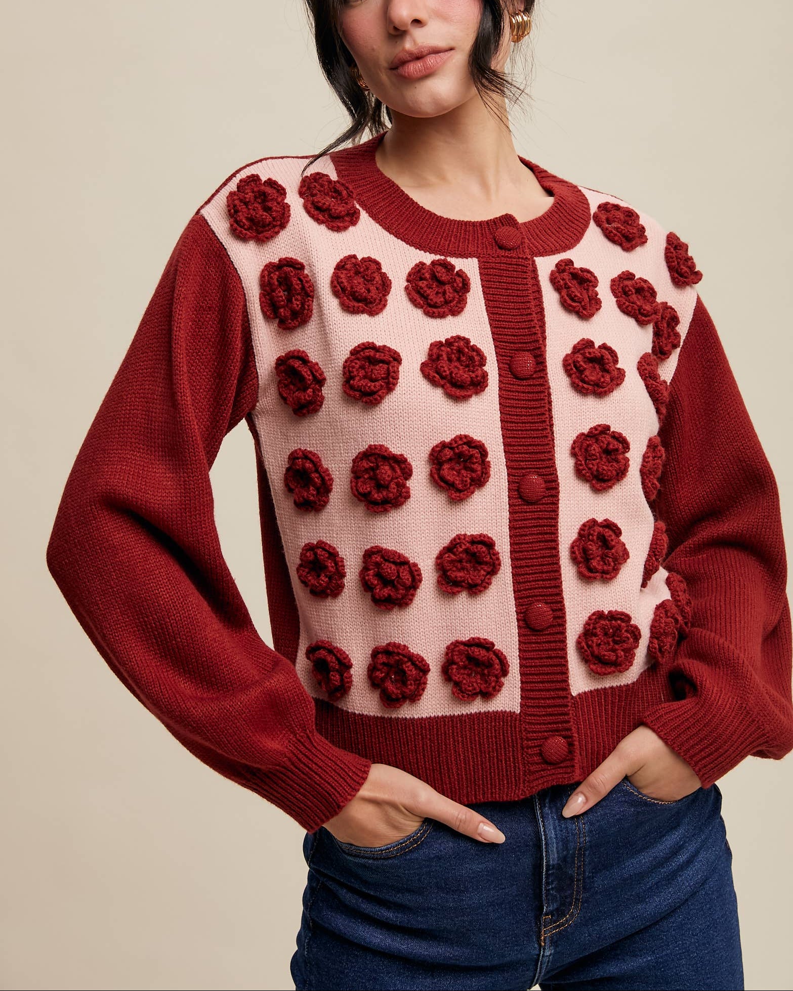 Woman wearing a red and pink floral patterned cardigan against a beige background