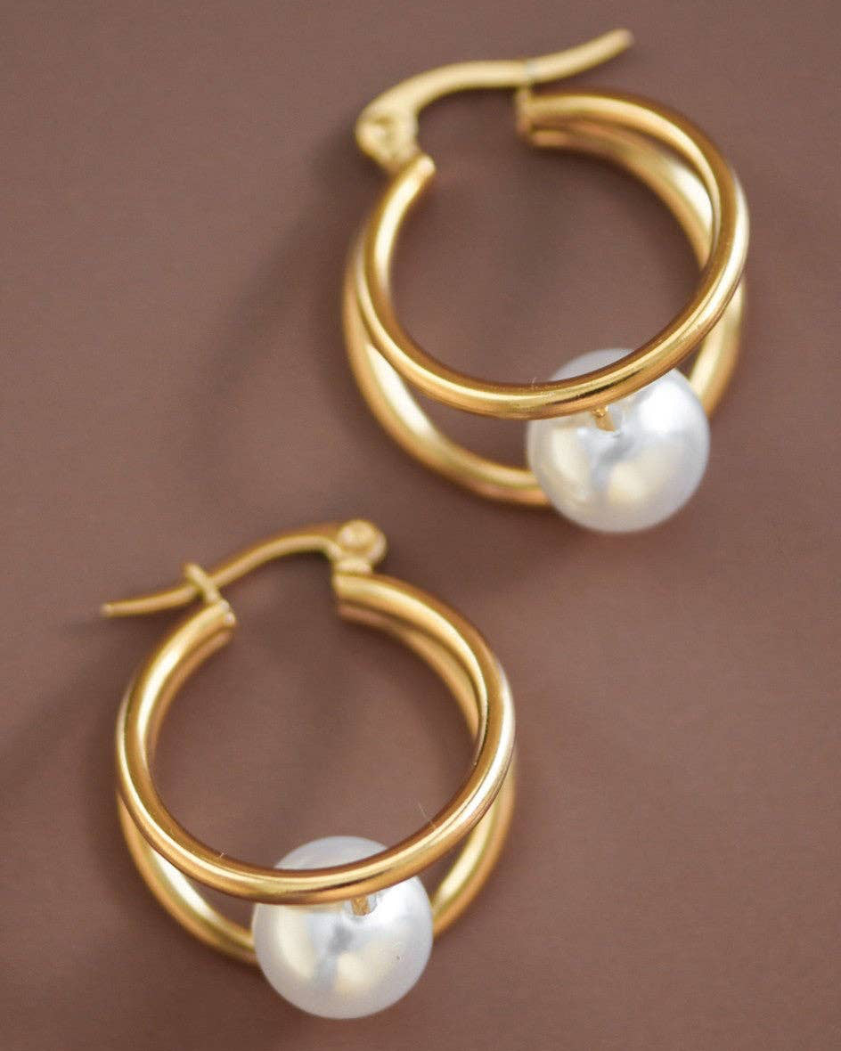 Gold hoop earrings with pearl accents on a brown background
