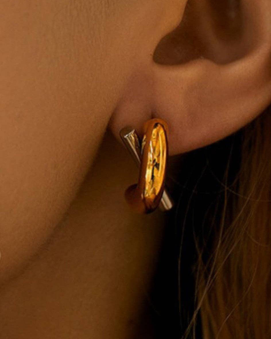 Gold hoop earring worn on an ear with a blurred background