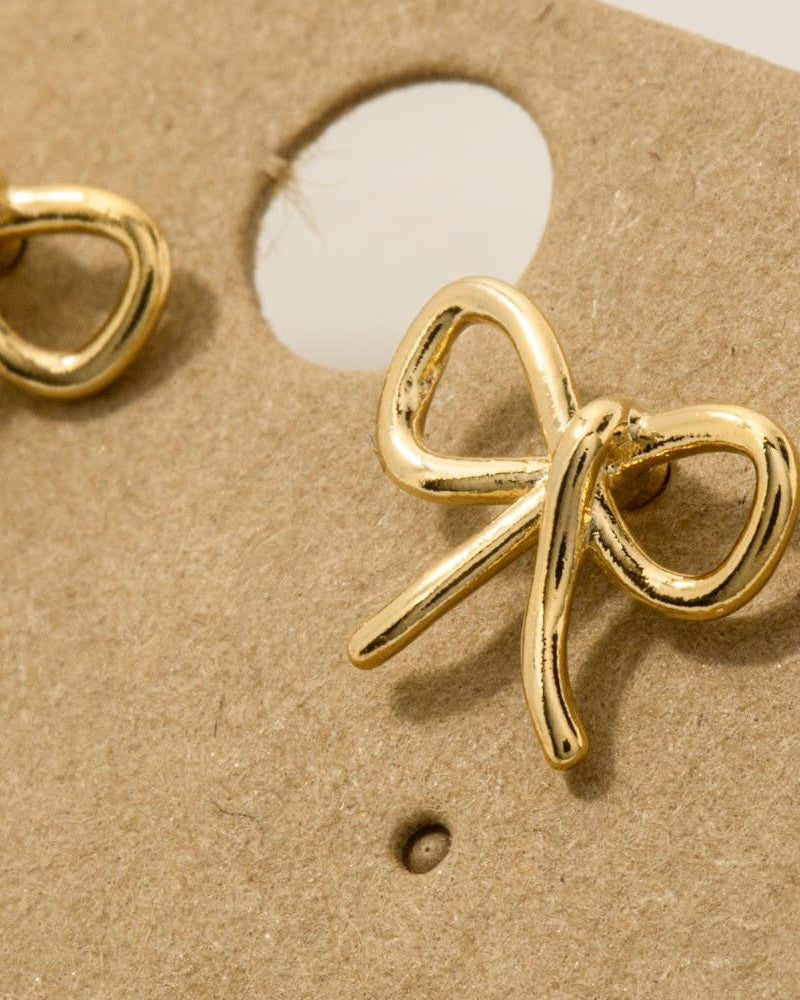 Gold bow-shaped earrings on a brown card
