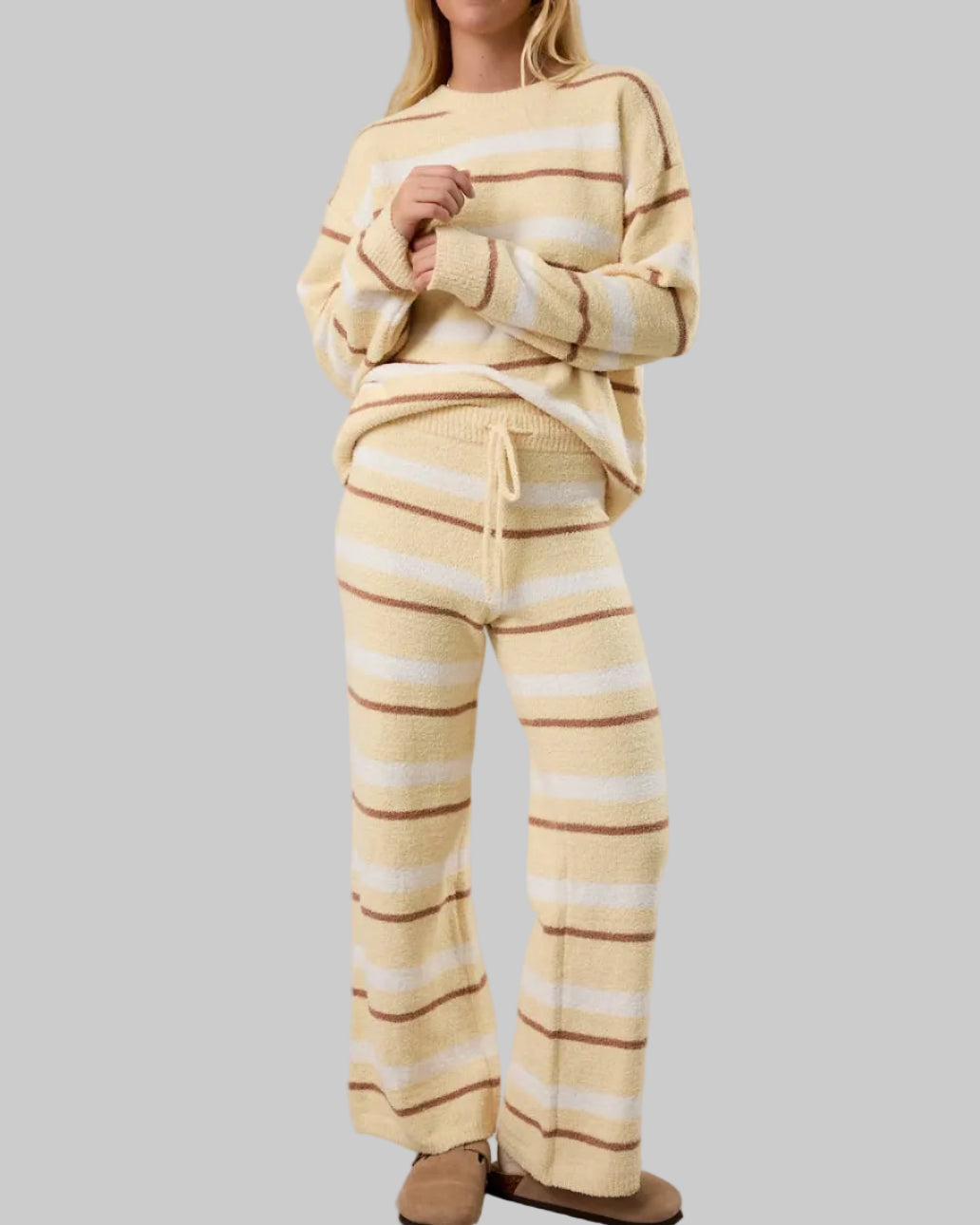 Woman wearing a yellow and white striped lounge set on a plain background