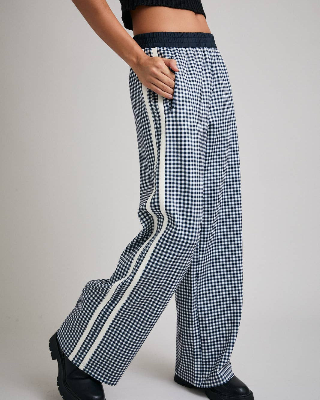 Person wearing black and white checkered pants with a stripe on a gray background